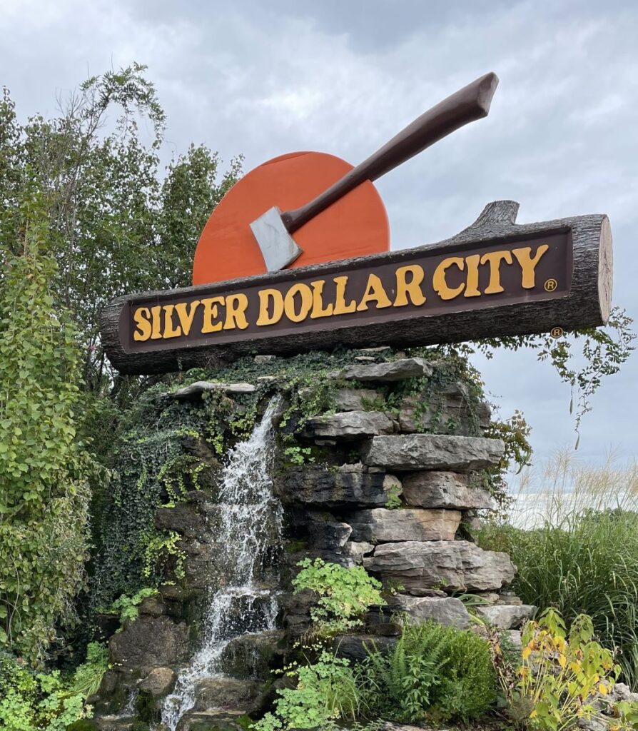 Silver Dollar City sign on top of small waterfall in parking lot