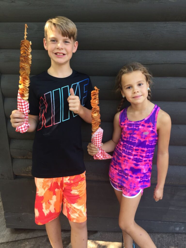 Two kid s proudly holding their Tater Twist from Silver Dollar City