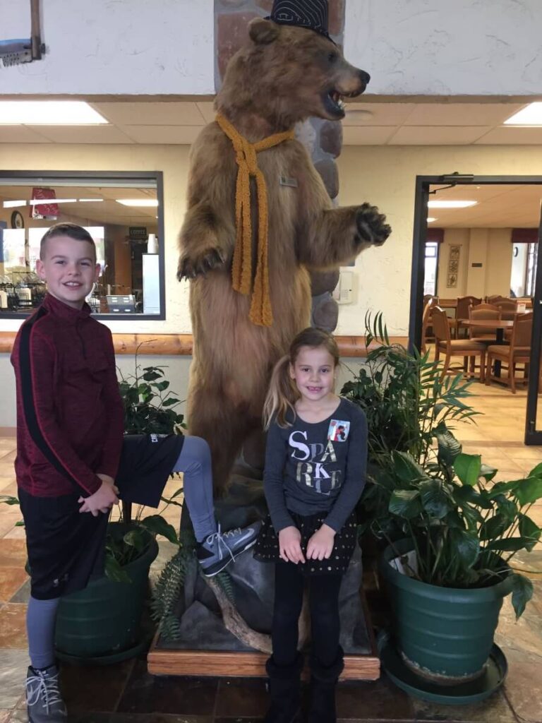 Kids standing near stuffed bear in lobby of Comfort Inn & Suites Branson Meadows.